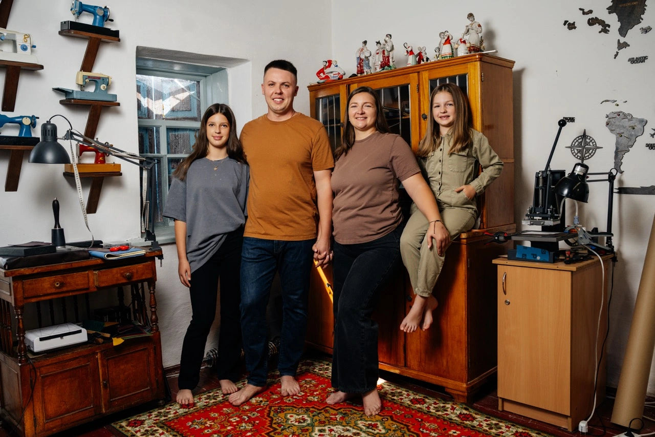 Four people standing in a room with wooden furniture and various items on shelves.