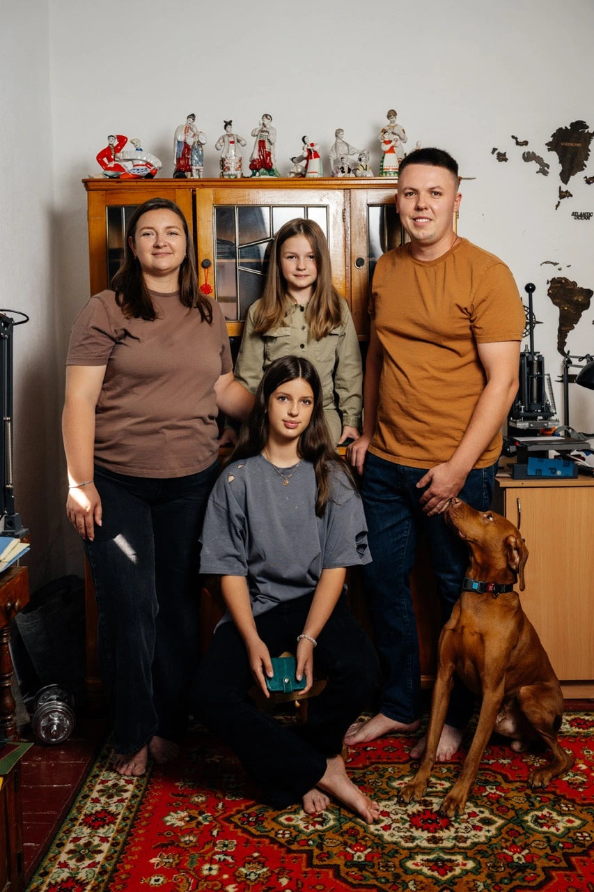 Family of four with a dog in a room with decorative items on shelves.